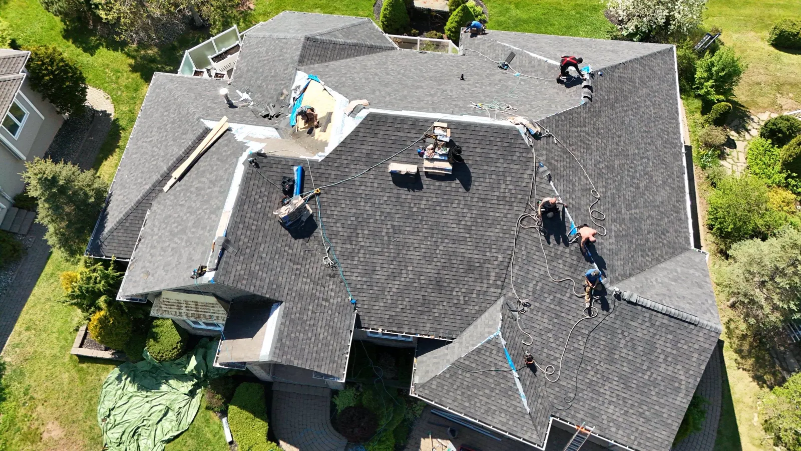 Top-down drone photo of the Plus Ultra crew spread across a new shingle roof mid-install