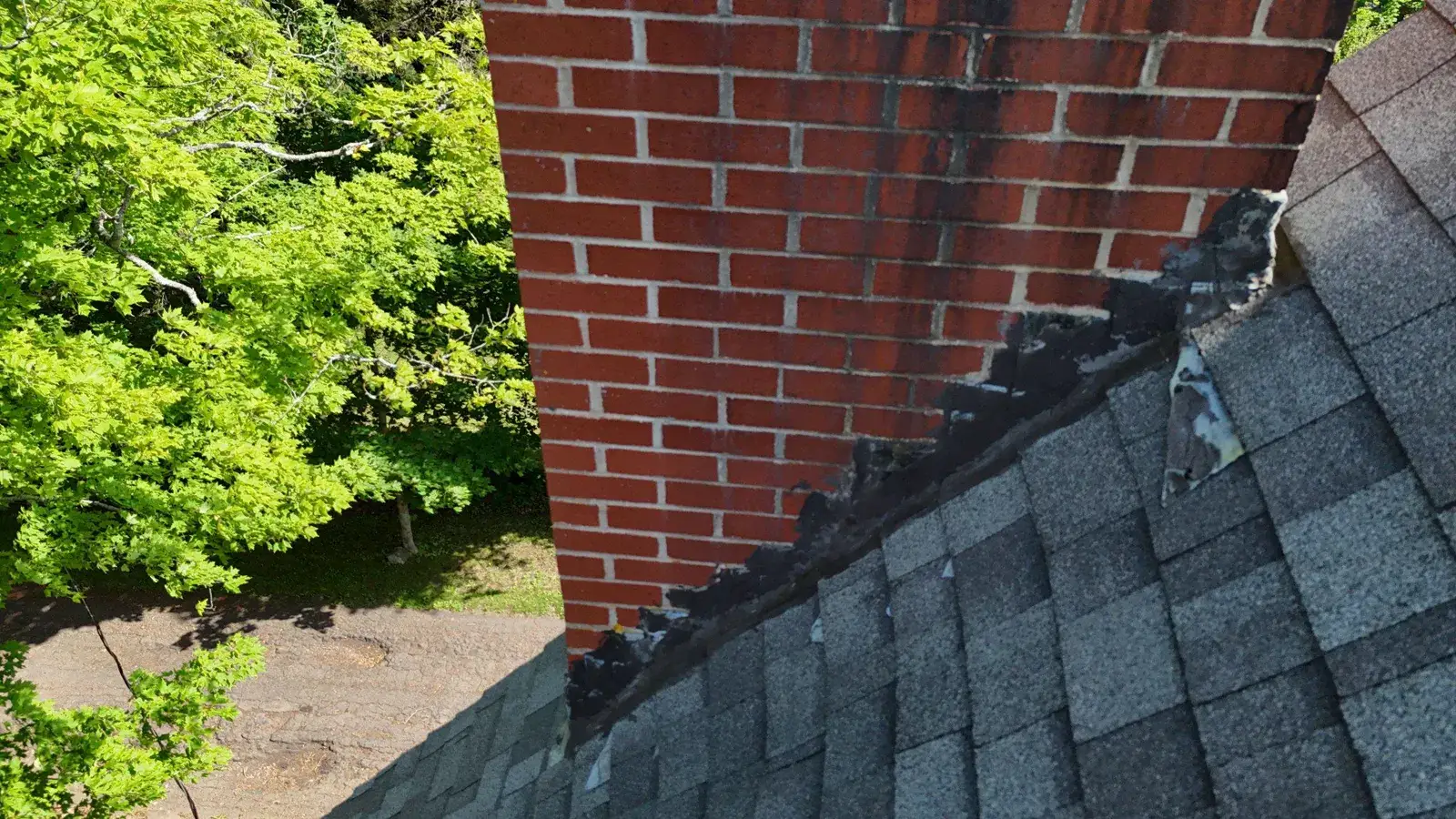 Failed chimney flashing awaiting roof repair in Sackville: tarred joints and lifting step flashing on aged shingles