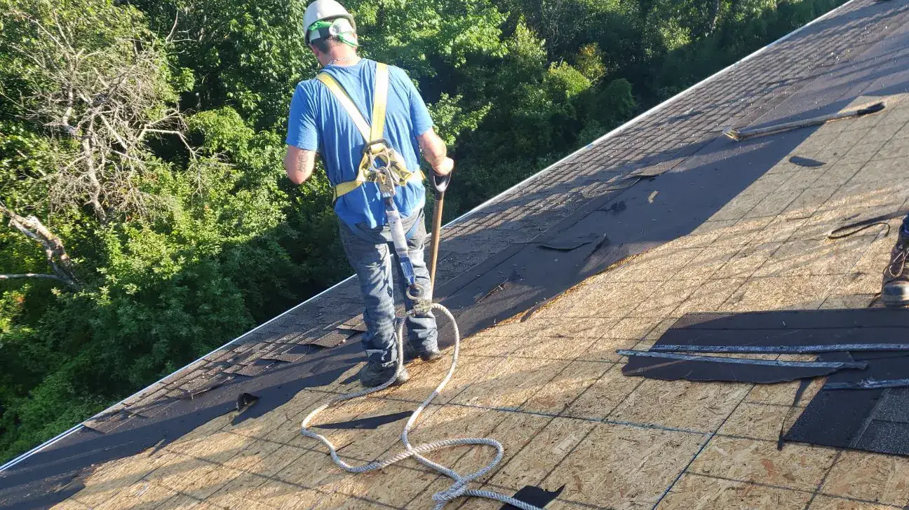 Plus Ultra roofer in a full safety harness on an open deck during a roof replacement in Fredericton