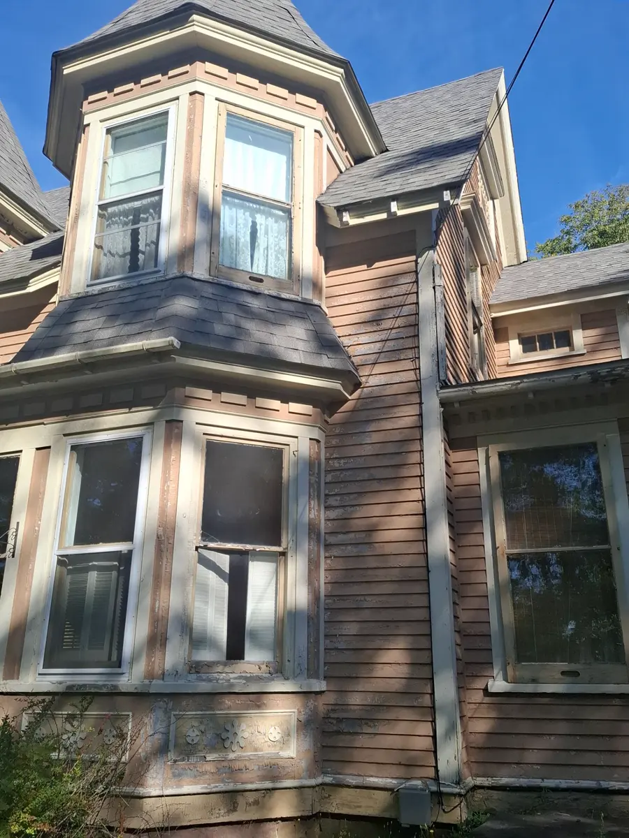 The witch-hat turret before: grey scalloped cone over the two-storey bay