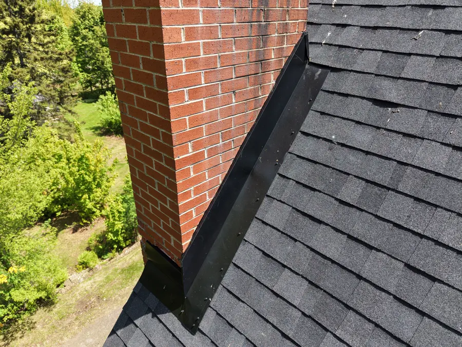 The same red brick chimney kept, now set in new black shingles