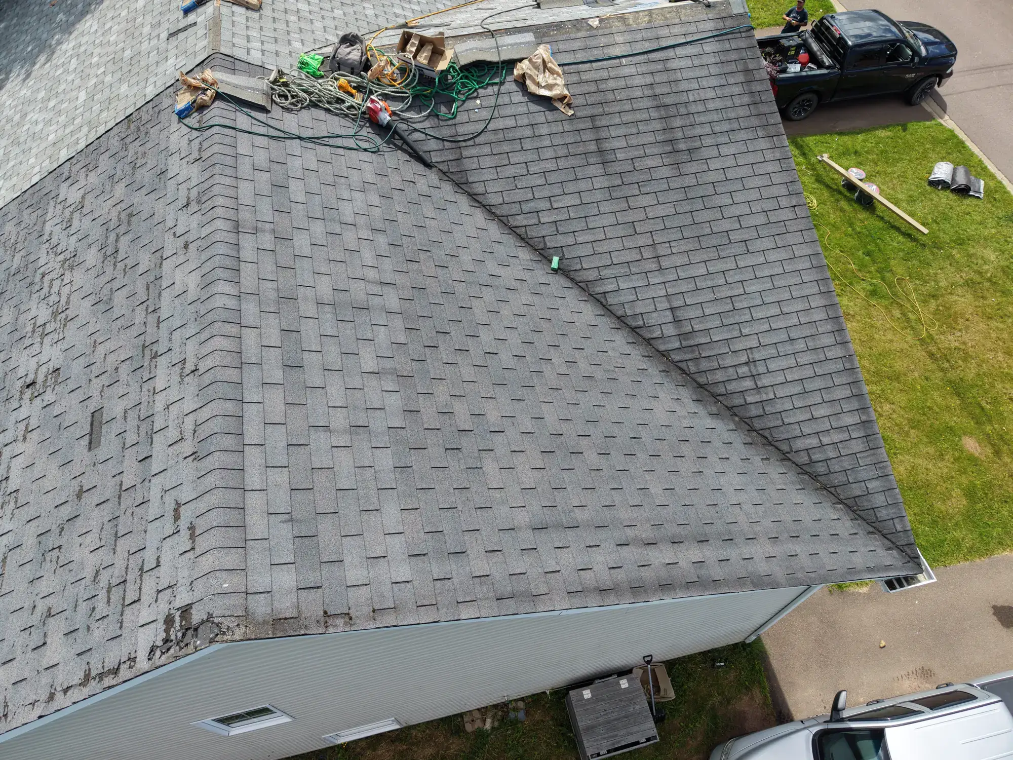 Worn, patched shingles at this Moncton duplex before Plus Ultra Roofing began the reroof