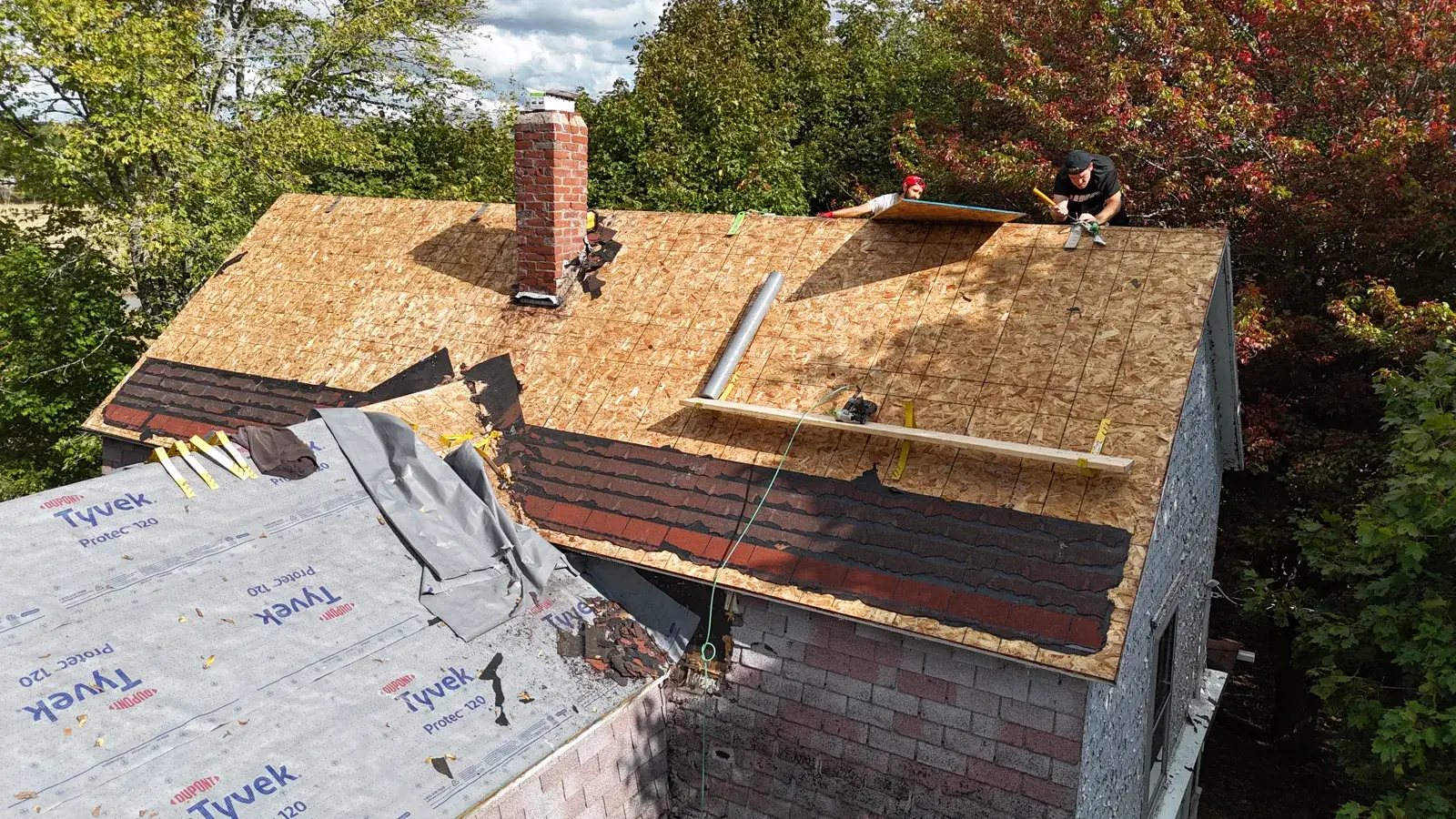 Our crew re-decking this New Brunswick home: old shingles stripped, fresh plywood going down